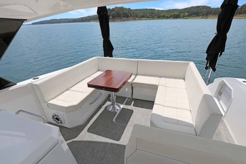 Slide: The Image of 2018 Cruisers Yachts 390 EC interior with white seating and wooden table on a lake. - 45