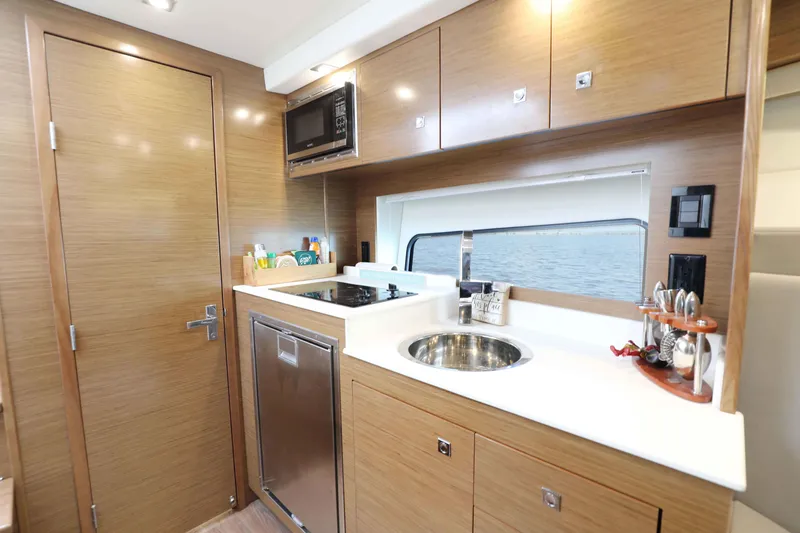 Slide: The Image of Modern kitchen interior of 2018 Cruisers Yachts 390 EC with wood cabinetry and stainless steel appliances. - 56
