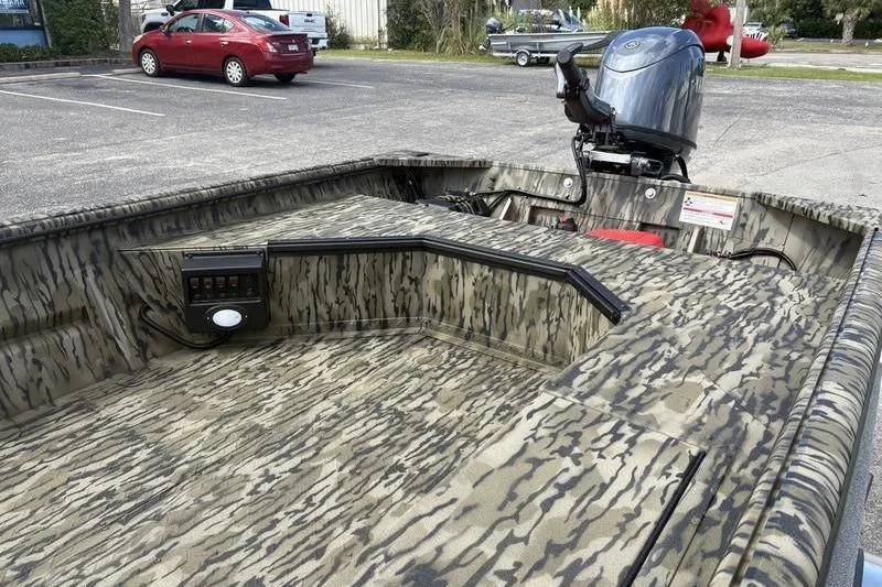 Slide: The Image of 2026 SeaArk DXS 1652 DKLD boat with camouflage design and outboard motor in parking lot. - 10