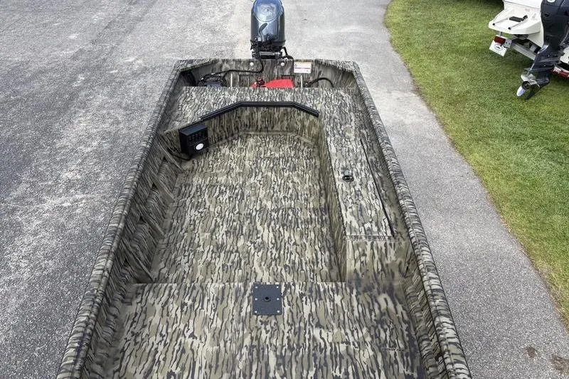 Slide: The Image of 2026 SeaArk DXS 1652 DKLD boat with camouflage design, parked on pavement. - 16