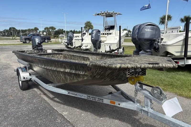 Slide: The Image of 2026 SeaArk DXS 1652 DKLD boat on trailer, camo design, parked outdoors. - 6