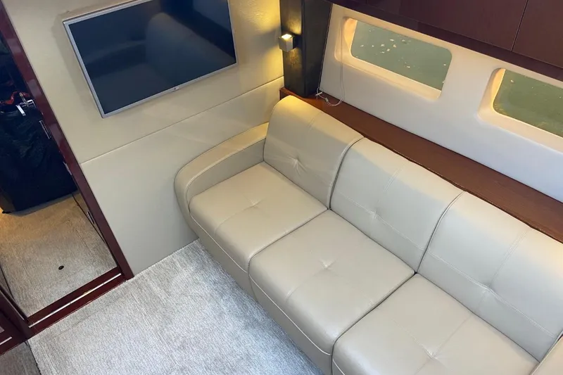 Slide: The Image of Interior of 2015 Sea Ray 470 Sundancer with beige sofa and wall-mounted TV. - 16