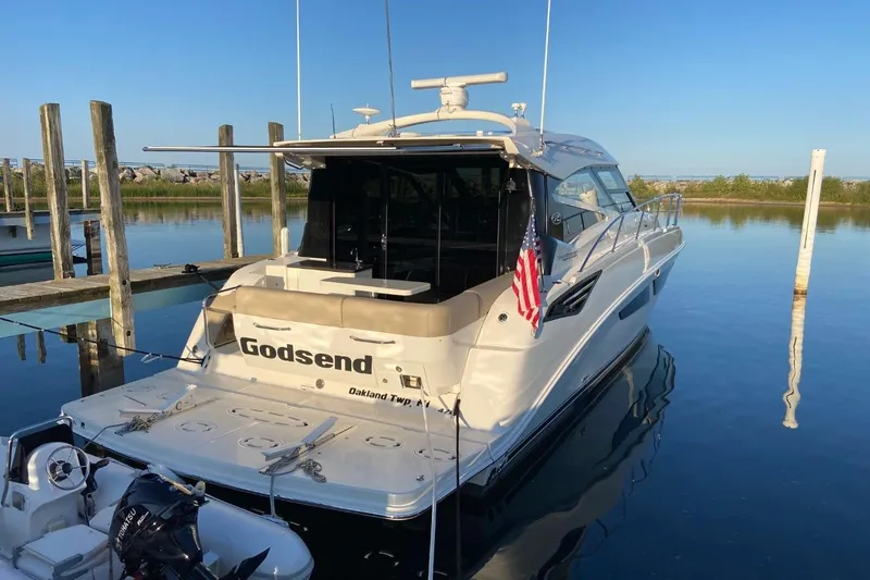 Slide: The Image of 2015 Sea Ray 470 Sundancer yacht docked, displaying American flag, calm water reflection. - 3