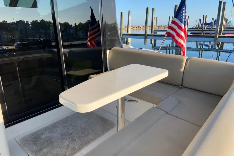 Slide: The Image of 2015 Sea Ray 470 Sundancer yacht with elegant seating and table, docked with American flag. - 51