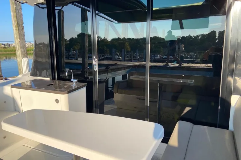 Slide: The Image of 2015 Sea Ray 470 Sundancer yacht interior with seating and kitchenette, docked by the water. - 52