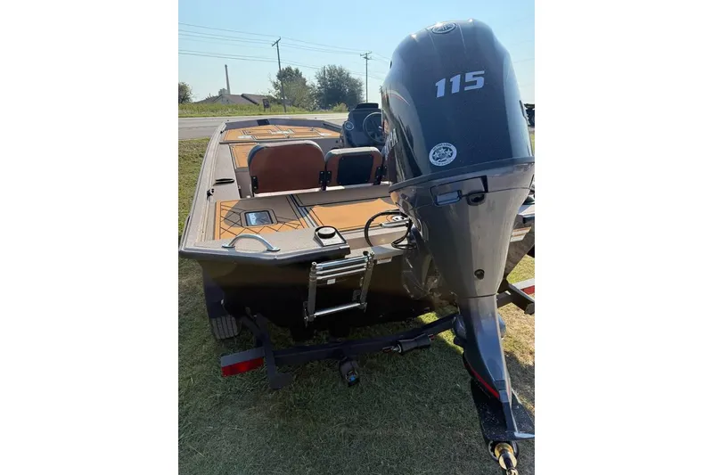 Slide: The Image of 2026 Avid 18 Rogue SC boat with 115 HP outboard motor, parked on grass. - 2