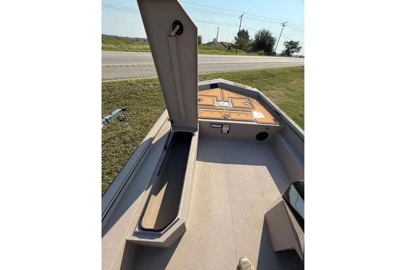 Slide: The Image of 2026 Avid 18 Rogue SC boat interior with open storage compartment, parked roadside. - 6