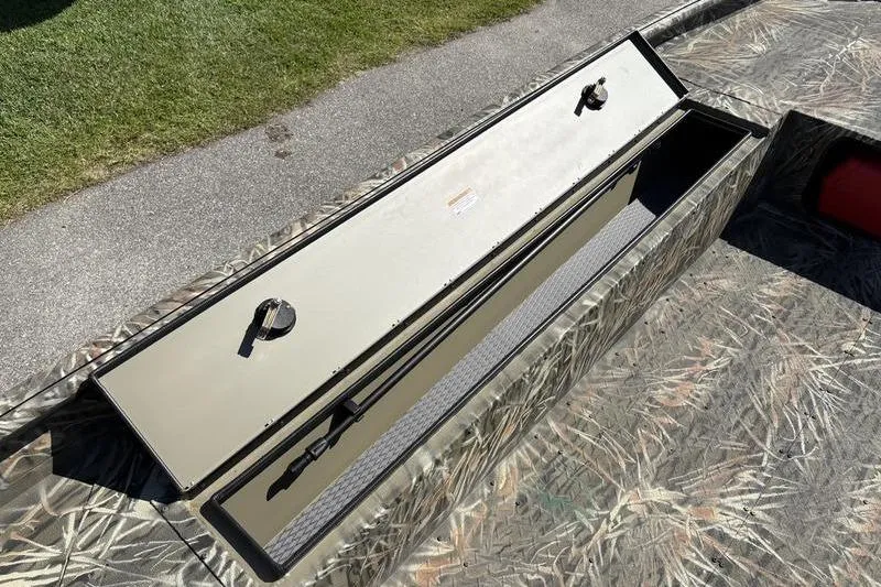 Slide: The Image of 2026 SeaArk 1960 Slayer boat with open storage compartment, camo design, and secure latches. - 13