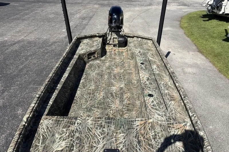 Slide: The Image of 2026 SeaArk 1960 Slayer boat with camouflage design, parked on pavement. - 16