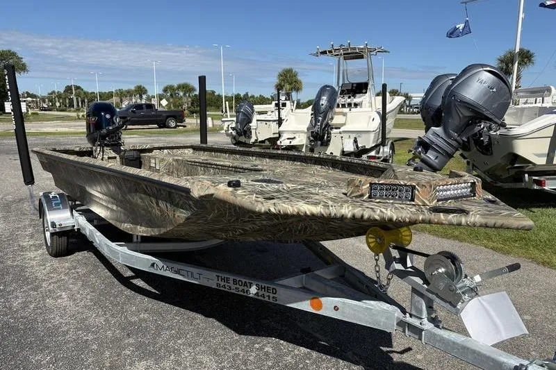 Slide: The Image of 2026 SeaArk 1960 Slayer boat on trailer, camo design, dual outboard motors, sunny day. - 6