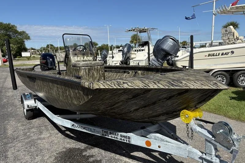 Slide: The Image of 2026 SeaArk Shadow 19 V Center Console boat on trailer, camo design, parked outdoors. - 13
