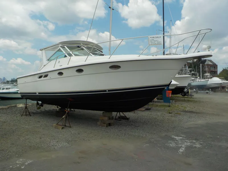 Slide: The Image of 2003 Tiara Yachts 3100 Open boat on stands, displayed for sale under a cloudy sky. - 1