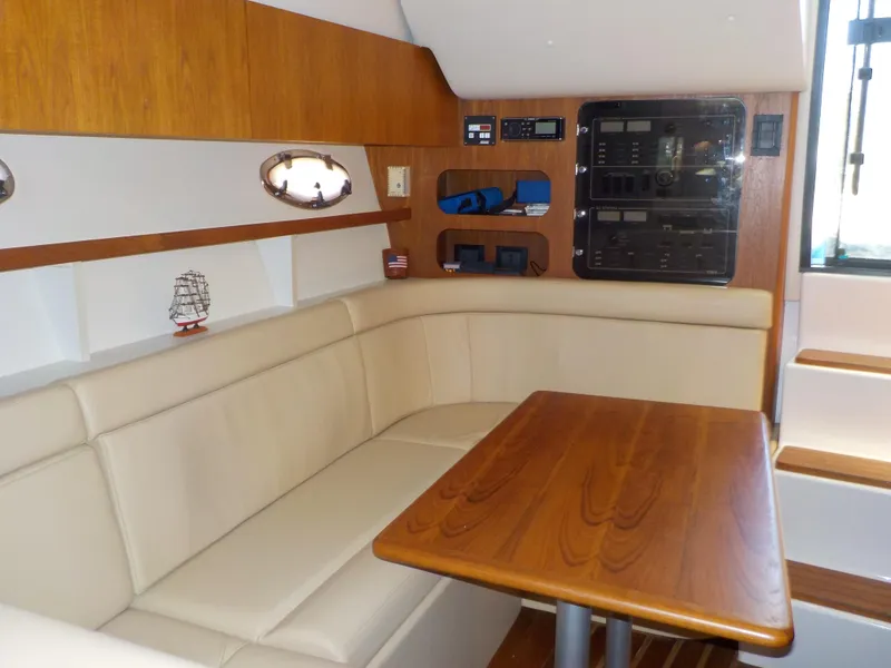 Slide: The Image of 2003 Tiara Yachts 3100 Open interior with beige seating and wooden table. - 12