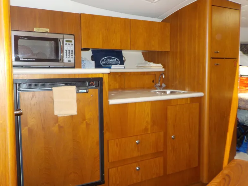 Slide: The Image of 2003 Tiara Yachts 3100 Open interior kitchen with microwave, sink, and wooden cabinetry. - 15
