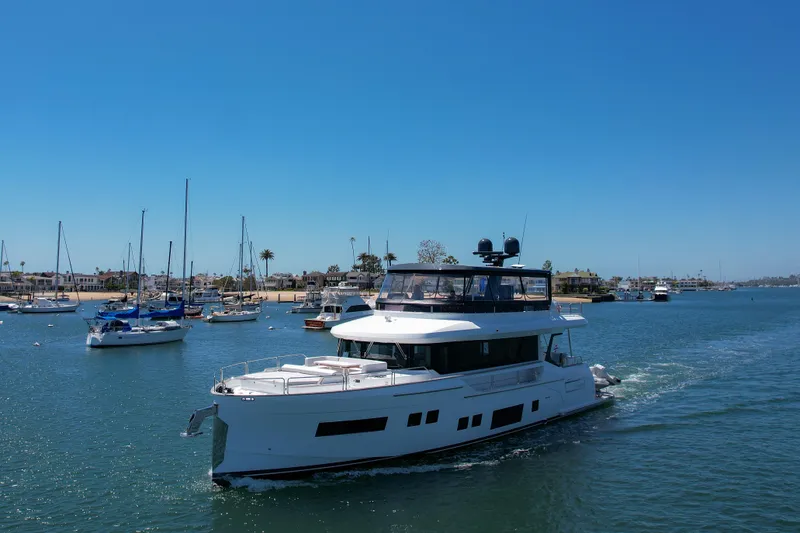 Slide: The Image of 2023 Sirena 68 yacht cruising in a marina with sailboats. - 2