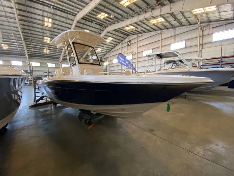 Slide: The Image of 2026 Scout 215 XSF boat in a spacious indoor showroom. - 2