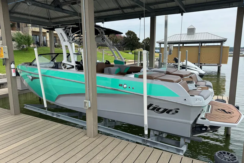 Slide: The Image of 2022 Tigé Z3 boat in dock, turquoise and white, with American flag. - 2