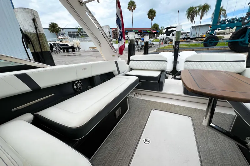 Slide: The Image of 2019 Regal 29 OBX boat interior with white seating and wooden table, dockside view. - 10