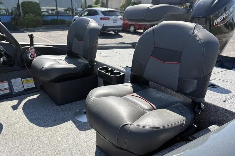 Slide: The Image of 2022 Tracker Pro Team 175 TF boat seats with cup holders, parked outdoors. - 9