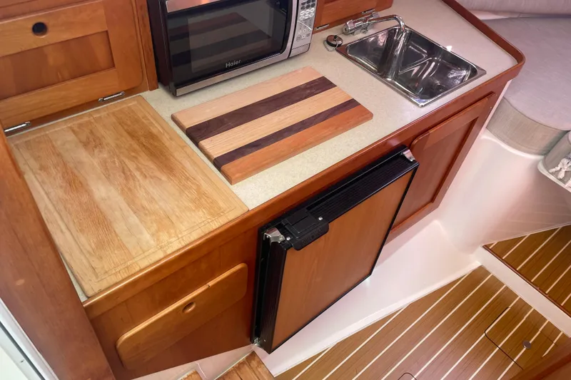 Slide: The Image of Compact kitchen area in a 2012 Hunt Surfhunter boat with wooden cabinetry and appliances. - 13