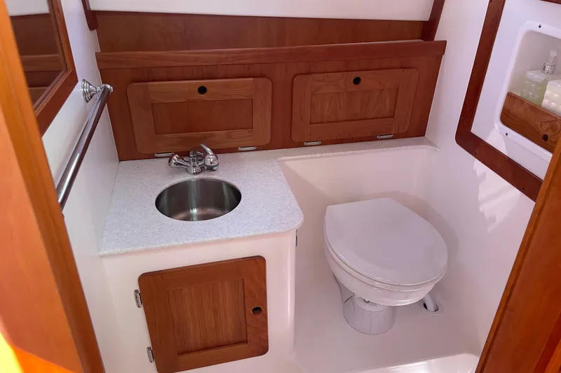 Slide: The Image of Compact boat bathroom with sink and toilet, featuring wooden cabinetry. Hunt Surfhunter 2012 model. - 18