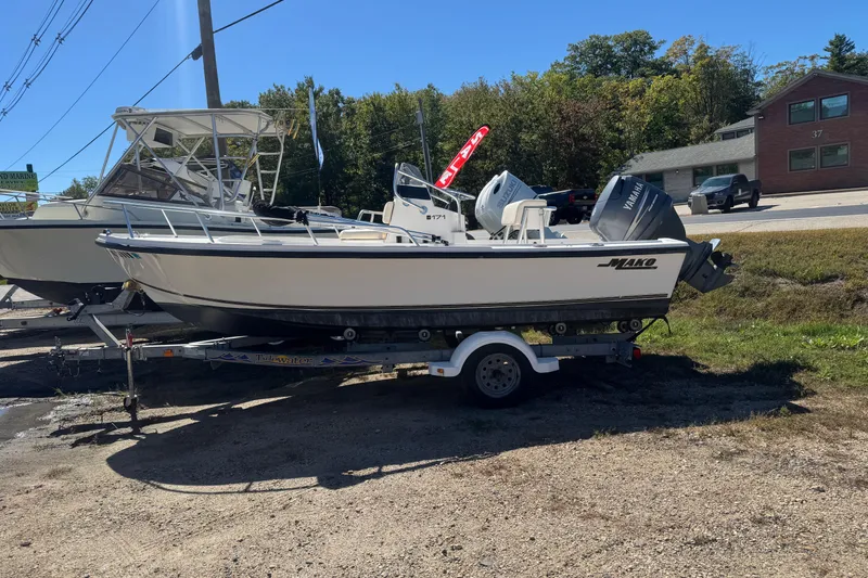 Slide: The Image of 2006 Mako 171 Center Console boat on trailer, parked outdoors in a sunny setting. - 2