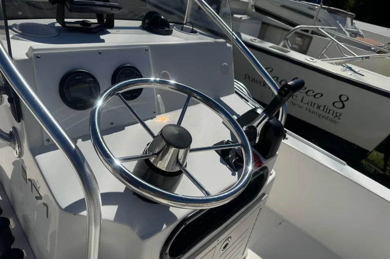 Slide: The Image of 2006 Mako 171 Center Console boat steering wheel and controls, docked near other boats. - 5
