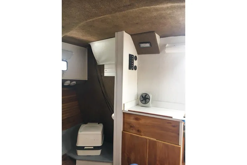 Slide: The Image of Interior of a 1980 SISU 26 boat featuring a compact cabin with a small fan. - 13