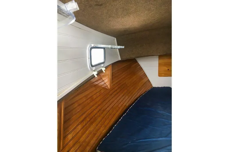 Slide: The Image of Interior of a 1980 SISU 26 boat cabin with wood paneling and a small window. - 14