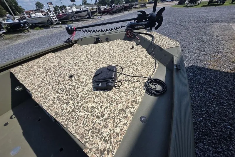 Slide: The Image of 2018 Tracker Grizzly 1648 boat with Minn Kota motor on gravel near metal building. - 3