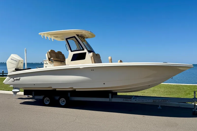 The Image of 2025 Scout 261 XSS boat on trailer by waterfront, clear blue sky background. - 0
