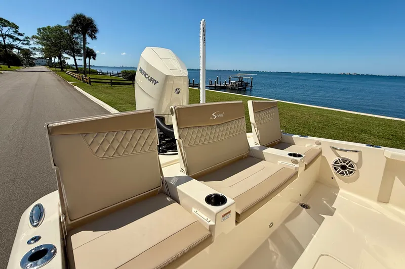 Slide: The Image of 2025 Scout 261 XSS boat interior with beige seating, near a scenic waterfront. - 12