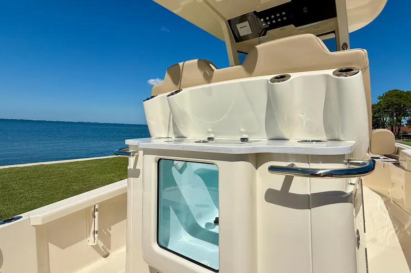 Slide: The Image of 2025 Scout 261 XSS boat interior with seating and storage, near a scenic waterfront. - 14