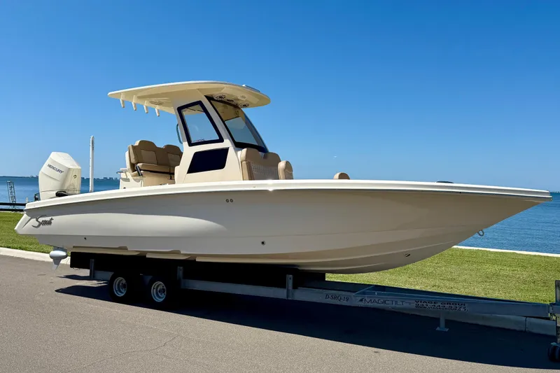 Slide: The Image of 2025 Scout 261 XSS boat on trailer by the waterfront under clear blue sky. - 3