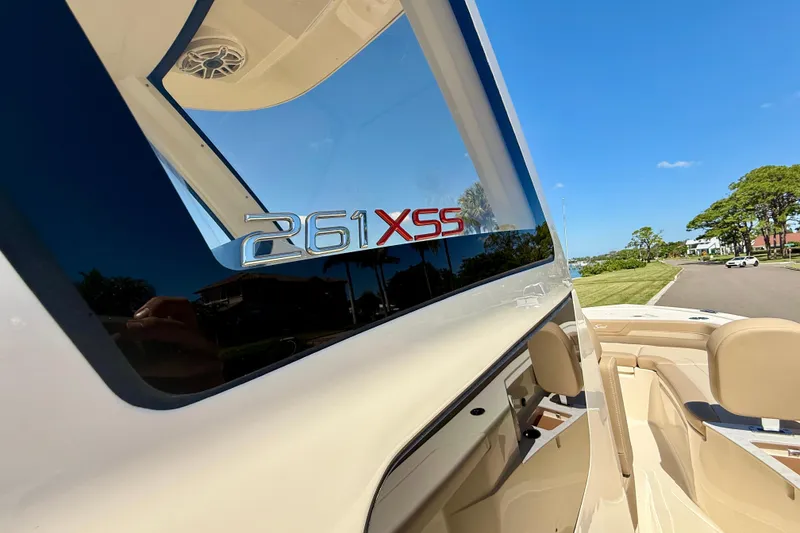 Slide: The Image of 2025 Scout 261 XSS boat, sleek design, beige interior, sunny day, waterfront view. - 35