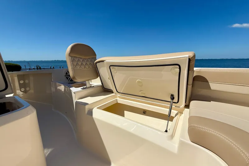 Slide: The Image of 2025 Scout 261 XSS boat interior with open storage compartment, beige seating, and ocean view. - 37