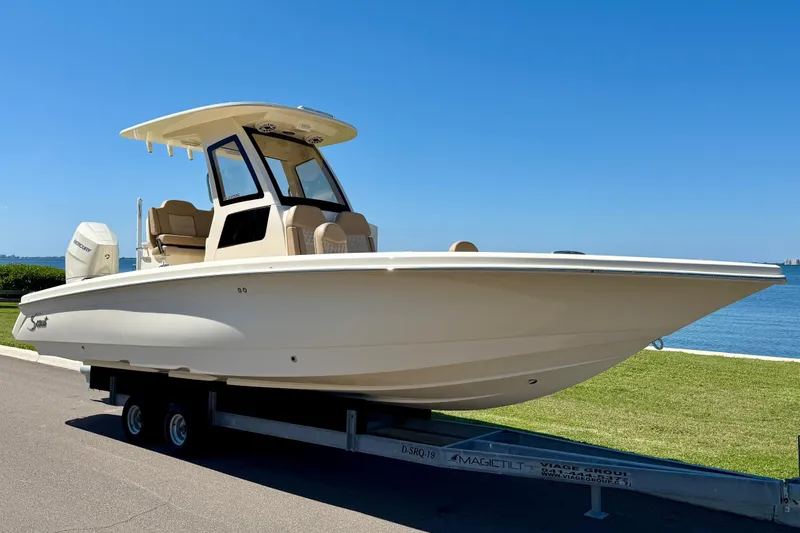 Slide: The Image of 2025 Scout 261 XSS boat on trailer by waterfront, clear blue sky. - 4