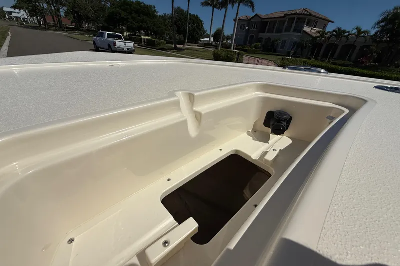 Slide: The Image of 2025 Scout 261 XSS boat storage compartment, open and empty, with a scenic background. - 40