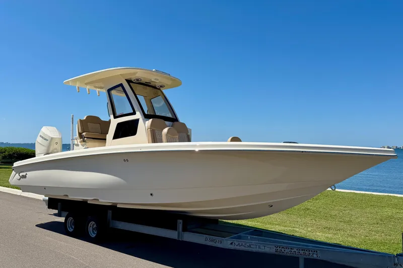 Slide: The Image of 2025 Scout 261 XSS boat on trailer by waterfront, clear blue sky. - 5