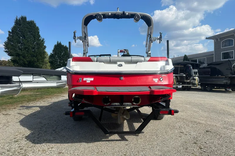 Slide: The Image of 2019 MasterCraft NXT20 boat, red and white, parked outdoors on gravel. - 2