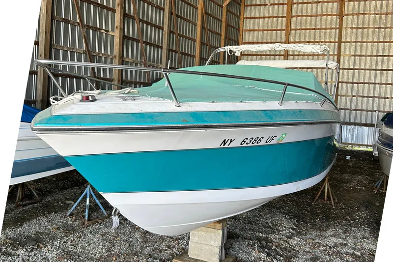The Image of 1991 Wellcraft 232 Eclipse boat in storage, teal and white exterior, covered and elevated. - 0
