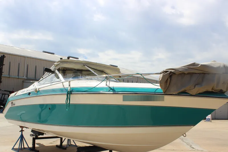 The Image of 1991 Wellcraft Eclipse 232 boat on stands, teal and white design, outdoor setting. - 1