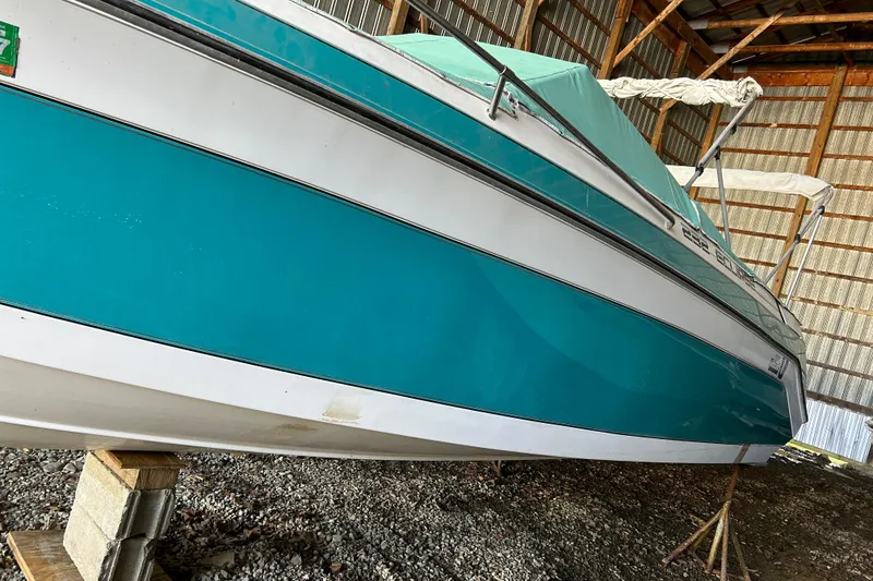 Slide: The Image of 1991 Wellcraft 232 Eclipse boat in storage, teal and white exterior, supported on blocks. - 17