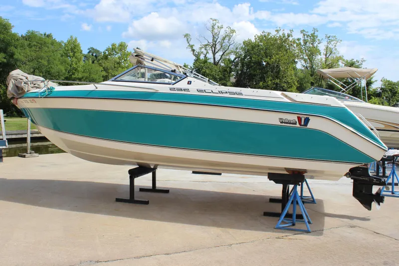 Slide: The Image of 1991 Wellcraft Eclipse 232 boat on stands, teal and white design, outdoors. - 5