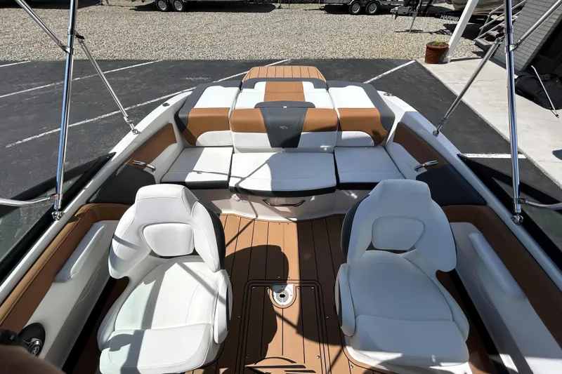 Slide: The Image of 2026 Chaparral 21 SSi boat interior with white and tan seating, docked outdoors. - 11