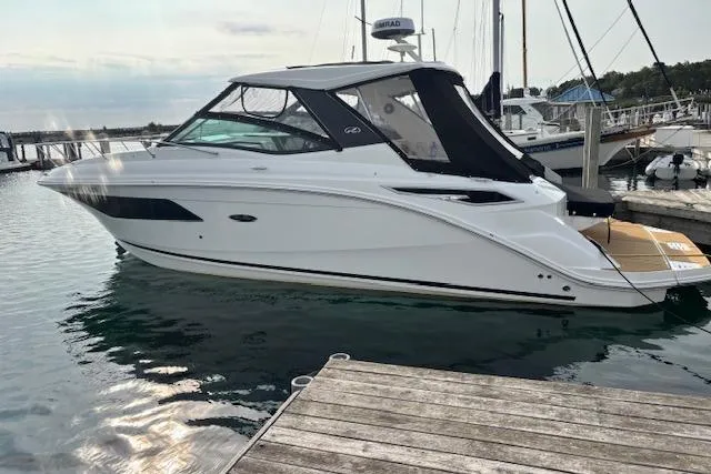 The Image of 2024 Sea Ray Sundancer 320 yacht docked at marina, sleek design, white hull, black canopy. - 0