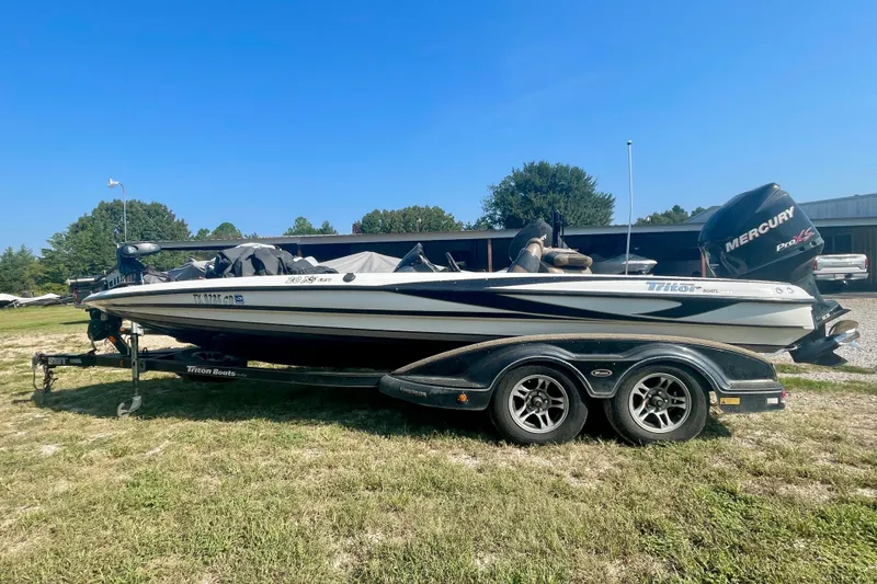 The Image of 2012 Triton 21 XS Elite boat on trailer, parked on grass under clear blue sky. - 0