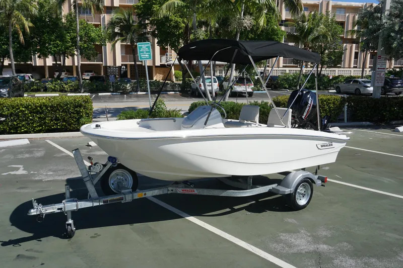 The Image of 2026 Boston Whaler 130 Super Sport boat on trailer in parking lot. - 0