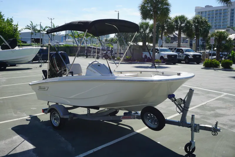 Slide: The Image of 2026 Boston Whaler 130 Super Sport boat on trailer in sunny parking lot. - 6