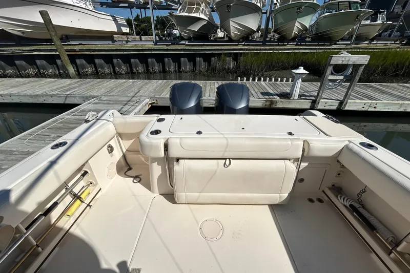 Slide: The Image of 2020 Grady-White Canyon 306 boat interior at dock, featuring dual engines and spacious seating. - 11